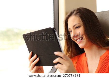 Happy passenger woman reading a tablet or ebook traveling inside a train
