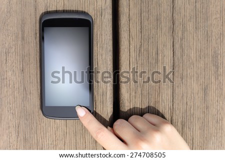 Woman finger pressing a blank smart phone touch screen with wooden background