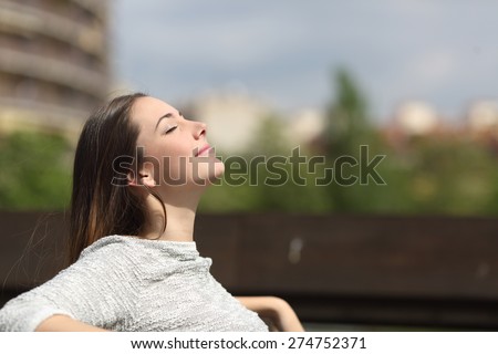 Urban woman sitting on a bench of a park and breathing deep fresh air