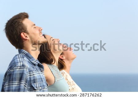 Group of three friends breathing deep fresh air on the beach