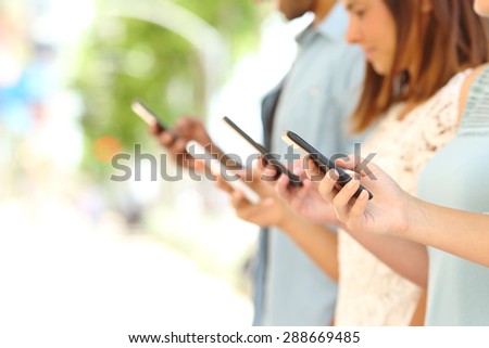 Four friend hands texting in their smart phones in the street with a blurred background