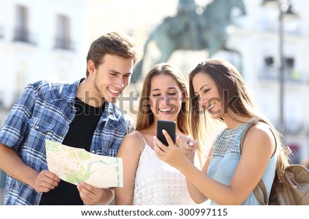 Three tourist friends consulting gps on smart phone in a touristic place with a monument in the background