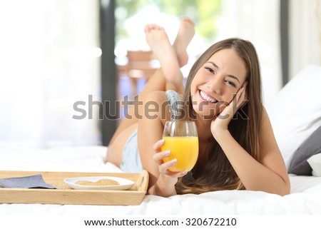 Happy girl having breakfast with orange juice on the bed at home and looking at camera Stok fotoğraf © 