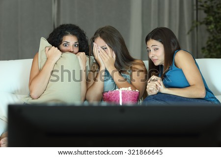 Girls watching a terror movie on tv sitting on a couch at home 商業照片 © 