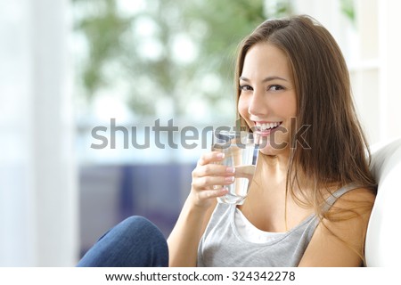 Girl drinking water sitting on a couch at home and looking at camera Foto d'archivio © 