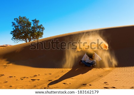 Berber playing and throwing with sands in Desert Sahara, creating angel with sands, Morocco
