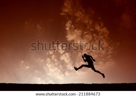 Silhouette of sport man jumping with blue sky and clouds on background