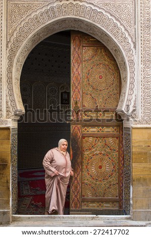 FEZ, MOROCCO - APRIL 19: Unkown woman going out from mosque, traditional morocco door in backgroun in April 19, 2015.