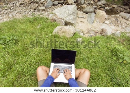 Man working in nature on his laptop over green grass