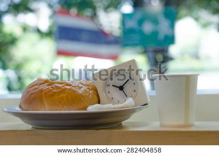 The clock displays the time ten o\'clock ten minutes in Breakfast dishes with a glass of white paper on mini bar at coffee shop in bangkok, thailand