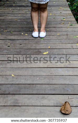 women stand alone with  white shoes on wooden way