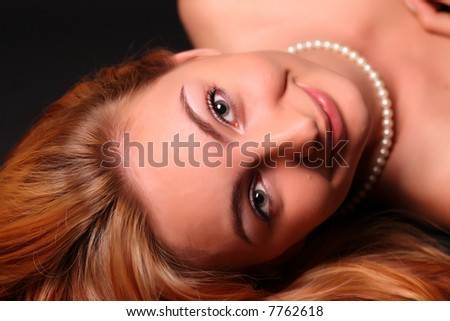 Portrait of ginger attractive and sexual young woman with pearl necklace over dark background
