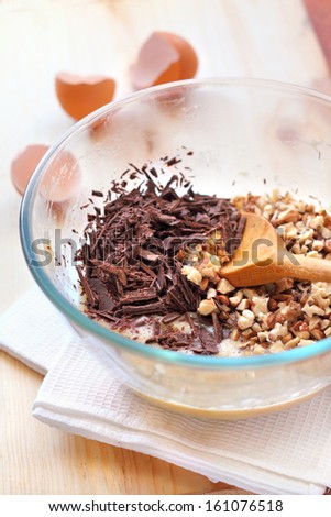 Chopped chocolate and walnuts in glass bowl in process of making Banana cake with walnuts and dark chocolate