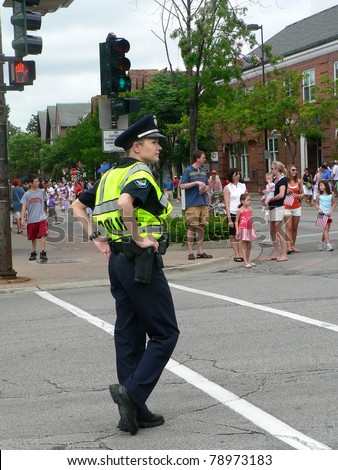 WINNETKA, ILLINOIS - JULY 4: An unidentified  female police officer watches a crowd of spectators at a Fourth of July parade on July 4, 2007 in Winnetka, Illinois.