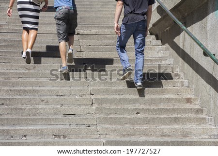 A woman and two man climbing on concrete stairs