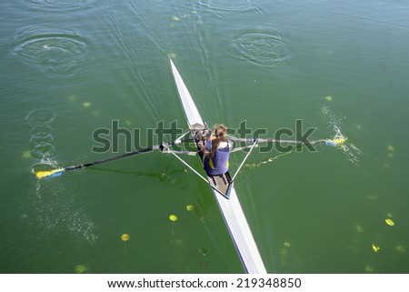 The woman rower in a boat, rowing on the tranquil lake