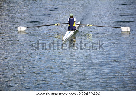 Rower in a boat, rowing on the tranquil lake