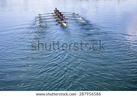 Boat coxed eight Rowers rowing on the tranquil blue lake