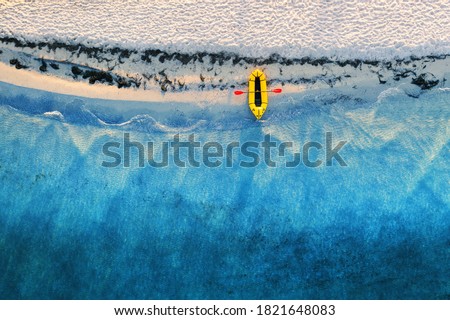 Yellow packraft rubber boat with red padle and turquoise water waves from top view. Beach with yellow sand glowing by sunlight. Travel summer vacations seascape background from drone Stock fotó © 
