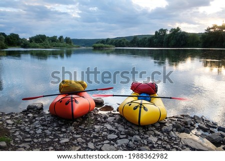 Orange and yellow packrafts rubber boats with padles ready for adventures on a sunrise river. Packrafting. Active lifestile concept Stock fotó © 