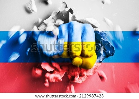 A fist punches through a concrete wall with the colors of the Ukrainian and russian flags. The concept of Ukraine crushes Russia army and won in war Stock foto © 