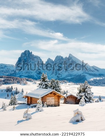 Picturesque landscape with small wooden log cabin on meadow Alpe di Siusi on sunrise time. Seiser Alm, Dolomites, Italy. Snowy hills with orange larch and Sassolungo and Langkofel mountains group Stok fotoğraf © 