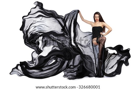Girl in black dress billowing out flying transparent fabric. Model on a white background holding a flying dress