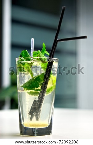 Glass of cool mojito cocktail on a white table with a background of interior cafe