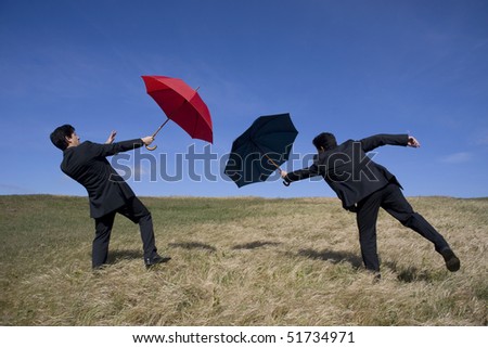 Business concept with two men holding umbrellas for protection
