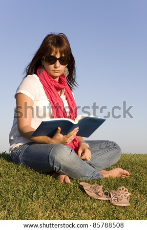 Beautiful woman reading a book on the park