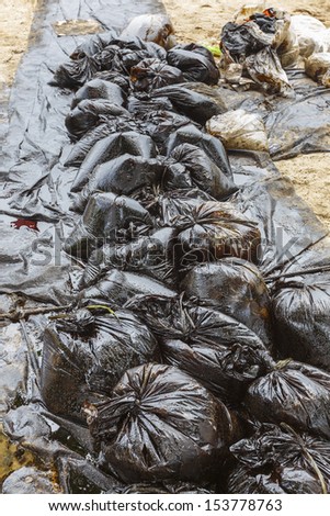 Row of Plastic bags which contain crude oil from the clean up operation on oil spill accident on Ao Prao Beach at Samet island on July 2013 in Rayong, Thailand.