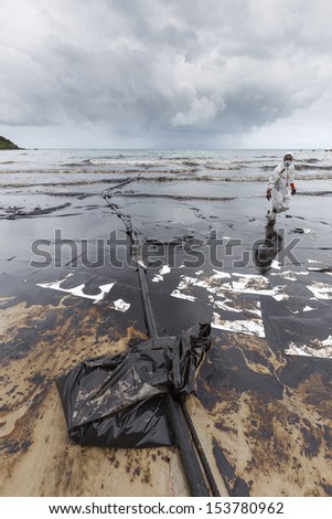 RAYONG, THAILAND - JULY 31, 2013: A worker in biohazard suit during the clean-up operation from crude oil spilled into Ao Prao Beach on July 31, 2013 in Rayong province, Thailand.