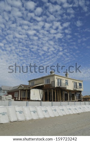 FAR ROCKAWAY, NY - OCTOBER 22: Damaged beach house in devastated area one year after Hurricane Sandy on October 22, 2013 in Far Rockaway, NY. Notice protective barrier build to prevent flooding
