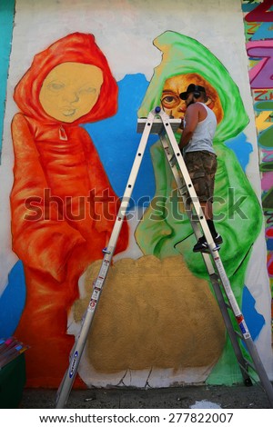 NEW YORK -MAY 12, 2015:Street artist Bob Plater painting mural at JMZ Walls in Brooklyn. A mural is any piece of artwork painted or applied directly on a wall, ceiling or other large permanent surface