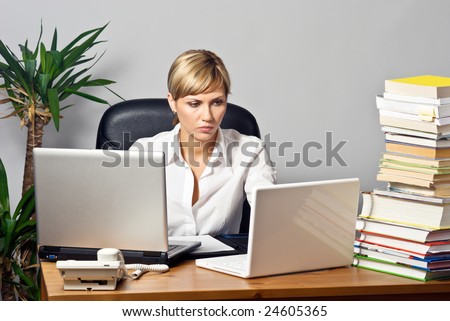 Young beautiful business lady at a table with two laptops.