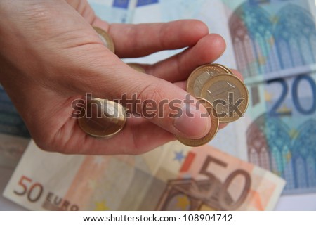 hand of a woman holding euro coins isolated on a background with euro bills