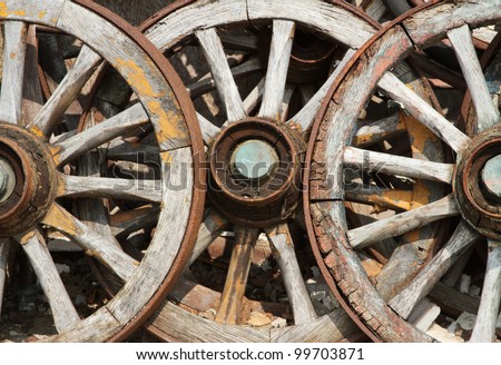 Three historic abandoned faded wooden cart wheels together