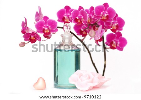 An orchid with a bottle of massage oil, heart and rose petal shaped soap.