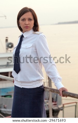 Portrait of the captain woman in the uniform with the ship on the background.