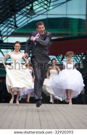 Laughing groom is escaping from the crowd of brides.