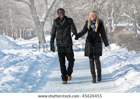 Romantic multi-etnic couple is walking in the winter park