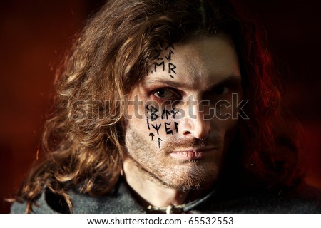 Portrait of a Medieval Knight with the runes on the face. Dark background.