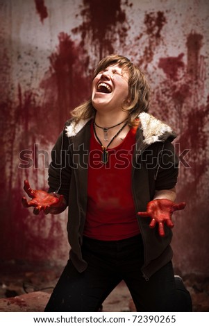 Crying woman with bloodstained hands on the bloody wall background
