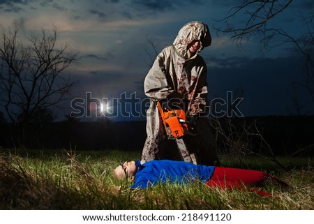 Maniac with the chainsaw dressed in a dirty bloody raincoat is killing the victim.
