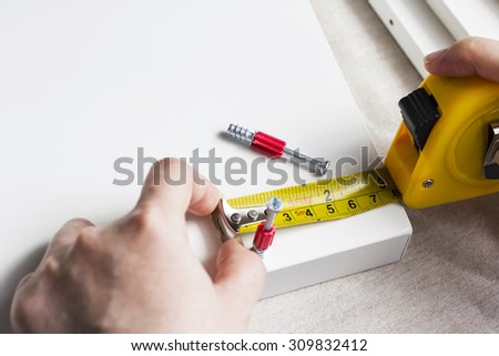 Young woman measuring home furniture with measure tape