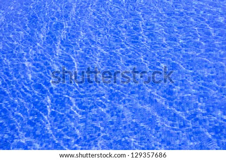 It is a very blue water pool. You can see small ripples in the water and mosaics on the floor of the pool
