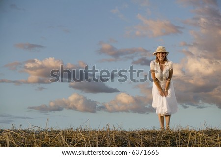 Wide angle shot of a woman against a cloudy sky at dusk.