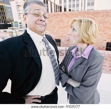 Executive woman sticks out her tongue at man on a downtown roof