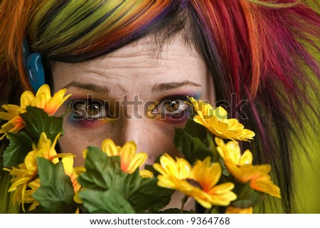 Pretty young woman peeks out from behind plastic flowers.