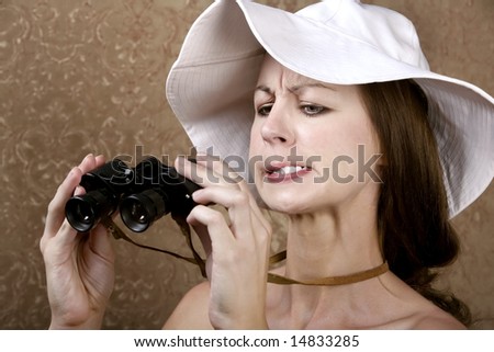 Young Woman with Sunglasses and a Floppy White Hat Looking through the Wrong End of Binoculars